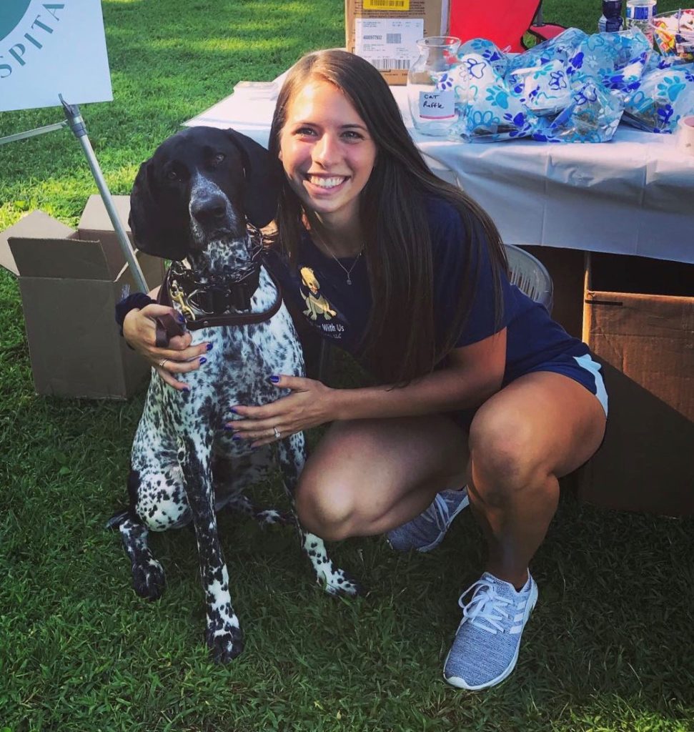 Bethany, a professional dog trainer, sitting and hugging a dog at a dog training event